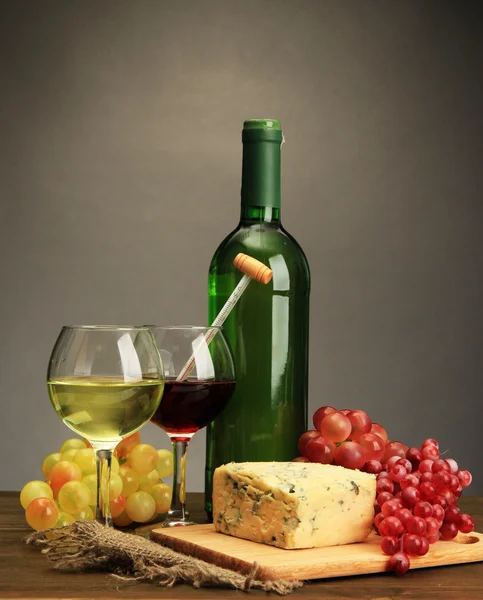 Komposition mit Wein, Blauschimmelkäse und Trauben auf Holztisch, auf grauem Hintergrund — Stockfoto