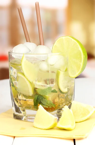 Glass of cocktail with lime and mint on white wooden table on bright background — Stock Photo, Image