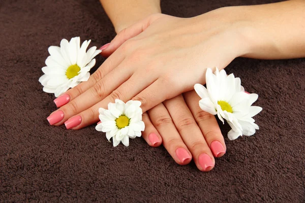 Mains de femme avec manucure rose et fleurs, sur fond de couleur — Photo