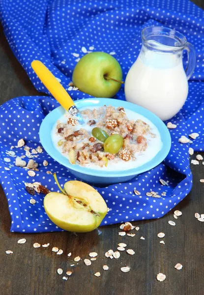 Useful oatmeal in bowl with fruit on wooden table close-up — Stock Photo, Image