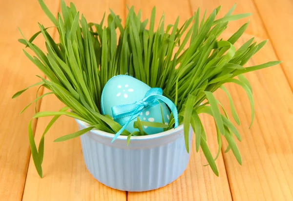 Huevo de Pascua en tazón con hierba sobre mesa de madera de cerca —  Fotos de Stock
