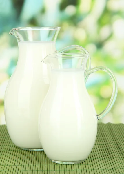牛奶在明亮的背景上的表上 pitchers — 图库照片