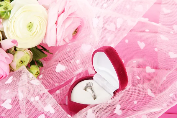 Ranunculus (tazas de mantequilla persa) y anillo de compromiso, en tela rosa —  Fotos de Stock