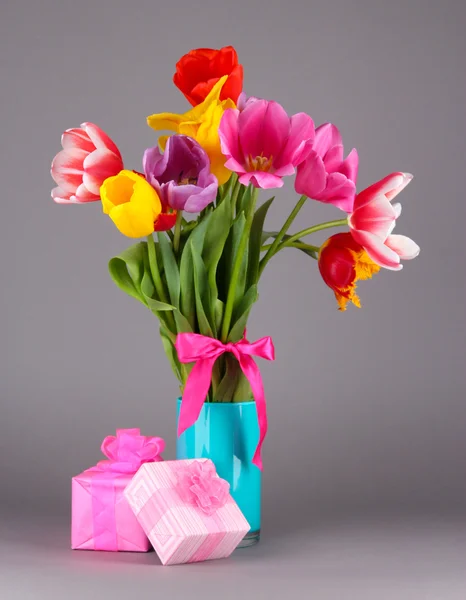 Hermosos tulipanes en ramo con regalos sobre fondo gris —  Fotos de Stock