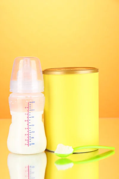 Bottle with milk and food for babies on orange background — Stock Photo, Image