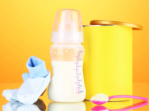 Bottle with milk and food for babies on orange background — Stock Photo, Image