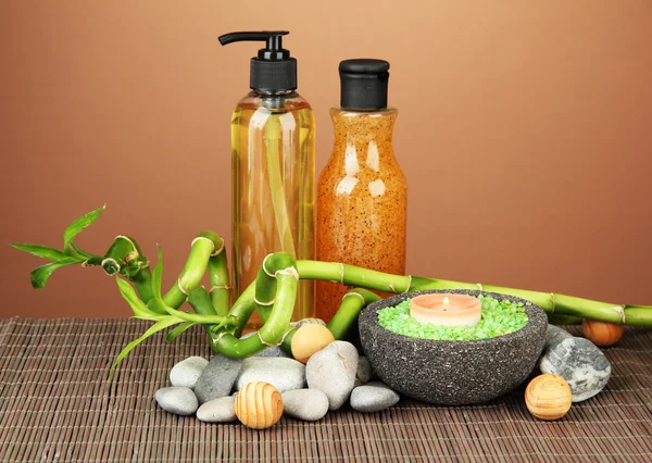 Still life with green bamboo plant and stones, on bamboo mat on color background — Stock Photo, Image