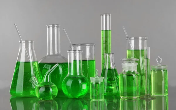 Tubos de ensaio com líquido verde sobre fundo cinzento — Fotografia de Stock