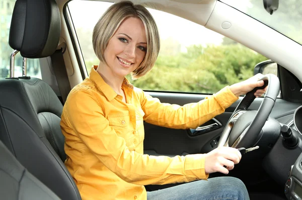 Portrait of young beautiful woman with key sitting in the car — Stock Photo, Image