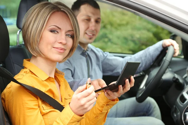 Retrato de una hermosa pareja joven sentada en el coche (mujer que aplica maquillaje ) —  Fotos de Stock