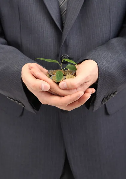 Jovem empresário com moedas e planta isolada no whit — Fotografia de Stock