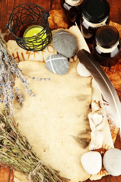 Composition with old papers, herbs, stones and bottles with symbols on wooden background — Stock Photo, Image