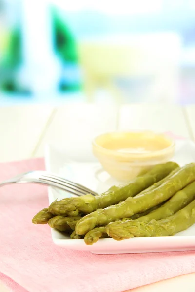 Asperges op plaat, op houten tafel op lichte achtergrond — Stockfoto