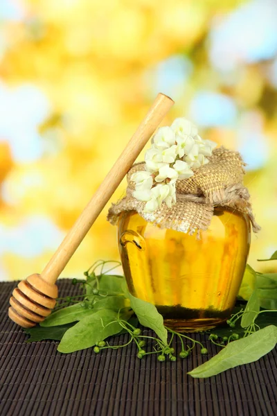Pot met honing met bloemen van kalk, op kleur bamboe mat op lichte achtergrond — Stockfoto