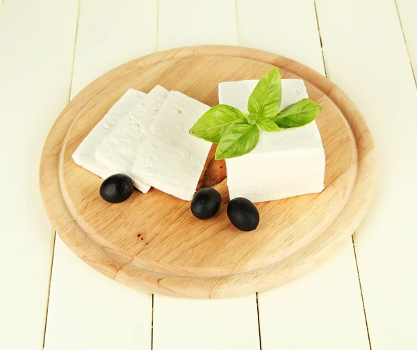 Queijo de leite de ovelha, azeitonas pretas, com manjericão sobre tábua de corte, isolado sobre branco — Fotografia de Stock