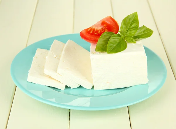 Sheep milk cheese, with basil and tomato on color wooden background — Stock Photo, Image