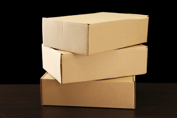 Cajas de paquetes sobre mesa de madera, sobre fondo negro — Foto de Stock