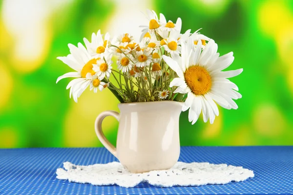 Beautiful bouquet chamomiles in pitcher on tablecloth on natural background — Stock Photo, Image