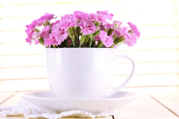 Muchos pequeños dientes de color rosa en taza sobre fondo de madera — Foto de Stock