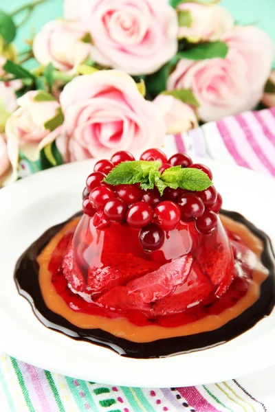 Tasty jelly dessert with fresh berries, on pink roses background — Stock Photo, Image