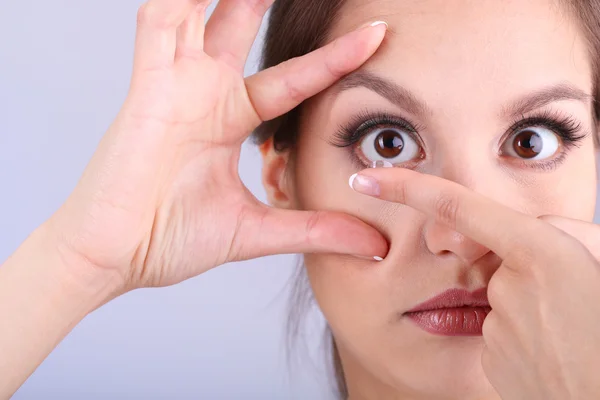 Young woman putting contact lens in her eye close up — Stock Photo, Image