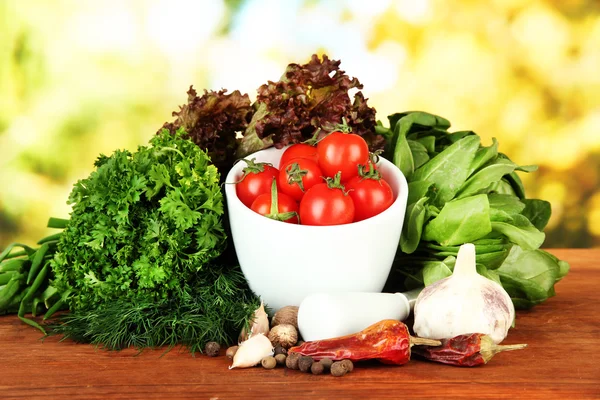 Komposition aus Mörser, Gewürzen, Tomaten und grünen Kräutern, auf hellem Hintergrund — Stockfoto