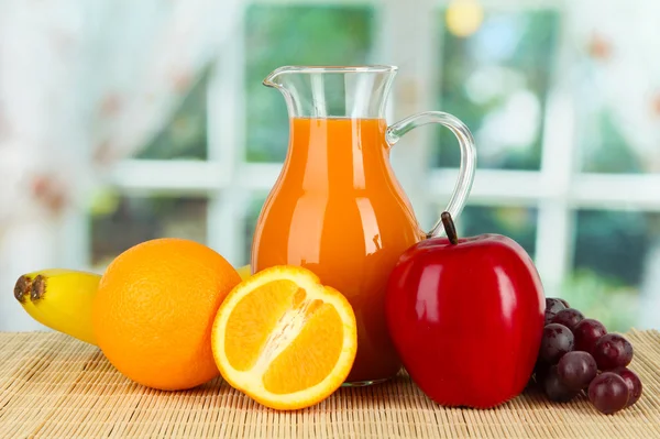 Orange juice in pitcher on table in room — Stock Photo, Image