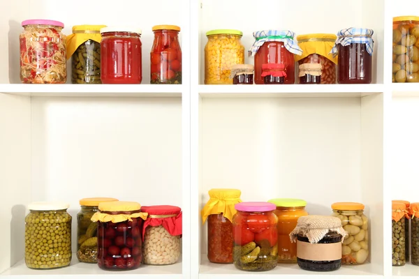 Different conservations on white shelves — Stock Photo, Image