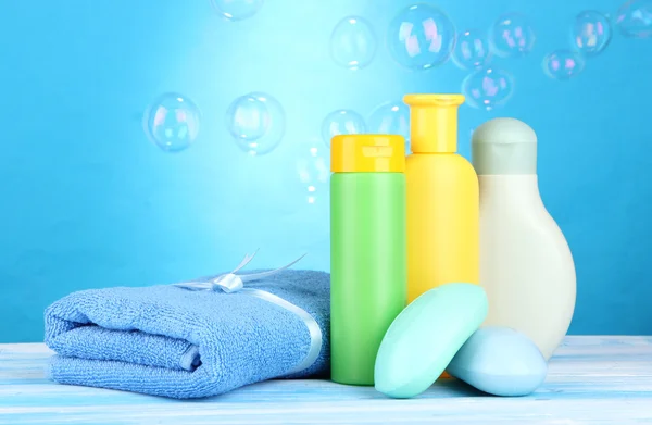 Cosméticos para bebés, toalla y jabón sobre mesa de madera, sobre fondo azul —  Fotos de Stock