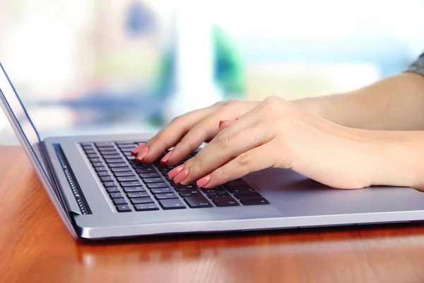 Las manos femeninas escribiendo en el portátil, sobre el fondo brillante — Foto de Stock