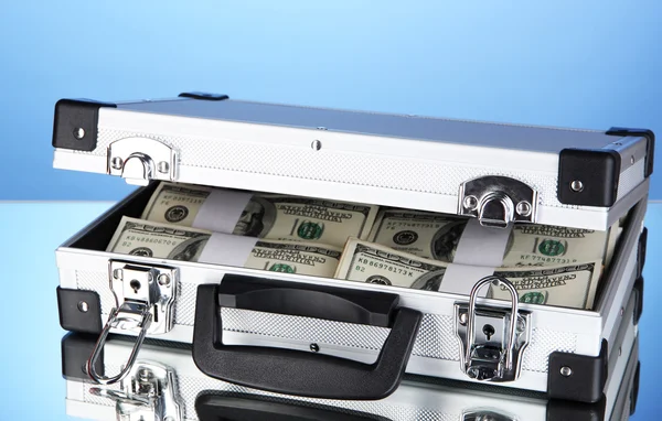 Suitcase with 100 dollar bills on blue background — Stock Photo, Image