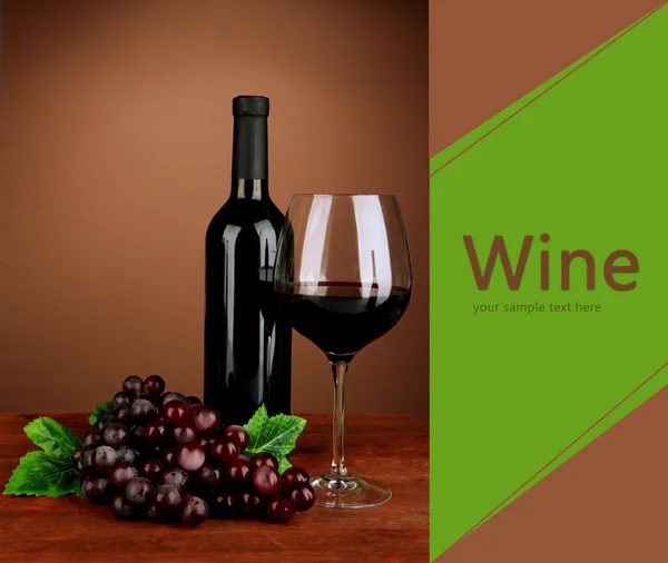 Composition of wine bottle, glass of red wine, grape on color background — Stock Photo, Image