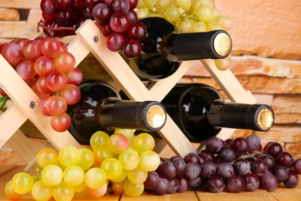 Botellas de vino colocadas sobre soporte de madera sobre fondo de pared de piedra — Foto de Stock