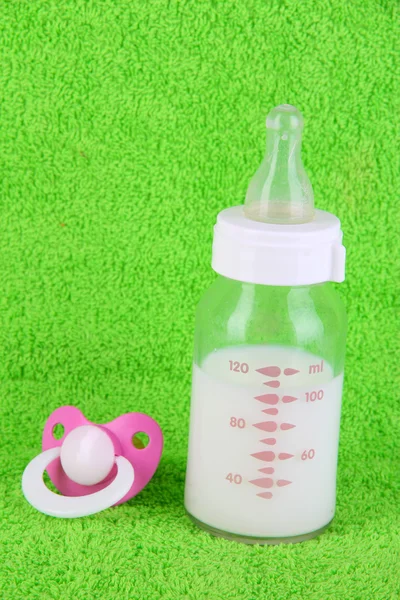 Botella para leche y pezón sobre fondo de toalla — Foto de Stock