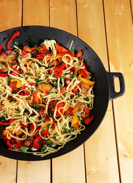 Noodles with vegetables on wok on wooden background — Stock Photo, Image