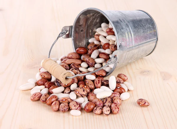 Overturned bucket with beans on wooden background — Stock Photo, Image