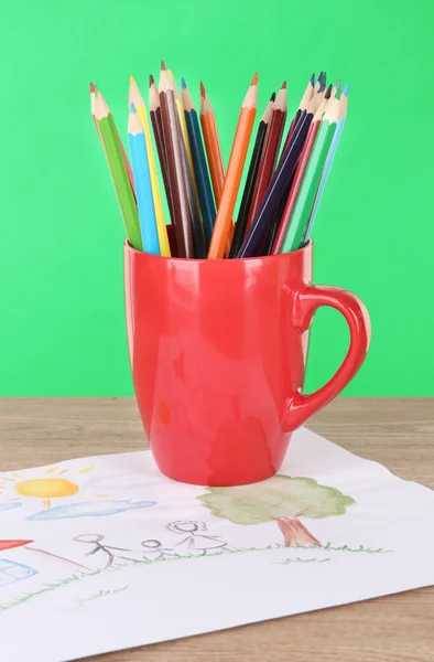 Colorful pencils in cup on table on green background — Stock Photo, Image