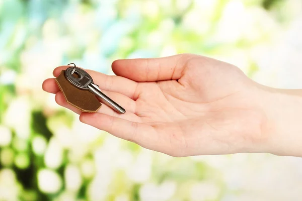 Key with leather trinket in hand on bright background — Stock Photo, Image