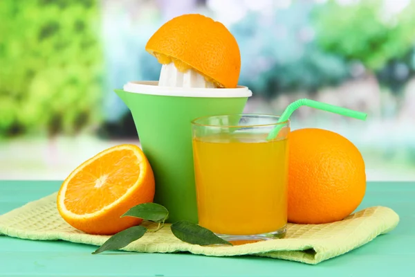 Citruspress, glas juice och mogna apelsiner på gröna träbord — Stockfoto