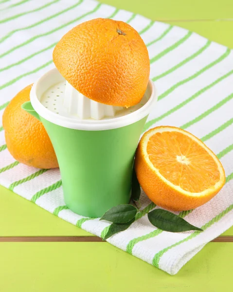 Citrus press and ripe oranges on green wooden table — Stock Photo, Image