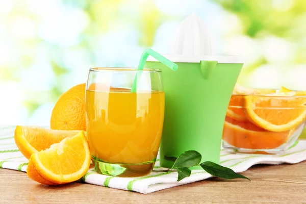 Citruspress, glas juice och mogna apelsiner på brun träbord — Stockfoto