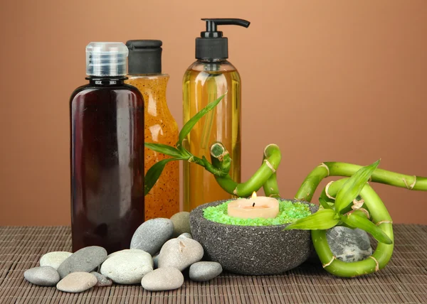 Still life with green bamboo plant and stones, on bamboo mat on color background — Stock Photo, Image