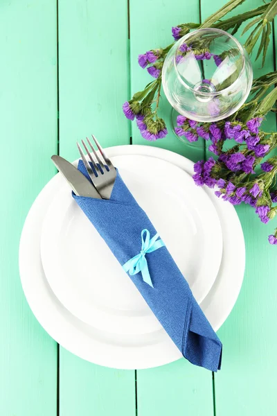 Knife and fork wrapped in napkin, on plate, on color wooden — Stock Photo, Image