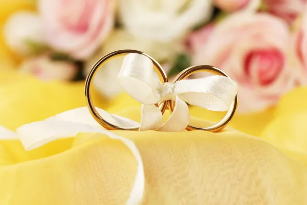 在明亮的背景上丝带绑的结婚戒指 — 图库照片
