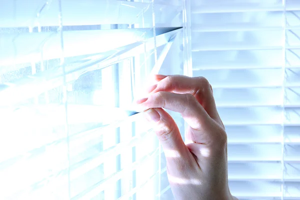 Someone looking out of window opening blinds — Stock Photo, Image