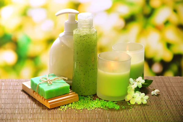 Cosmetics bottles and natural handmade soap on green background — Stock Photo, Image