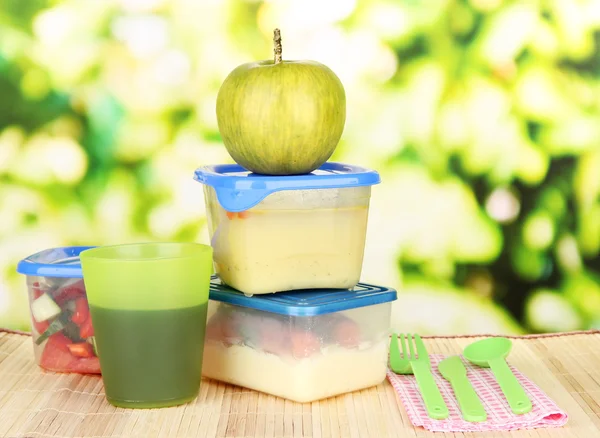 Smakelijke lunch in plastic verpakkingen, op bamboe mat op lichte achtergrond — Stockfoto