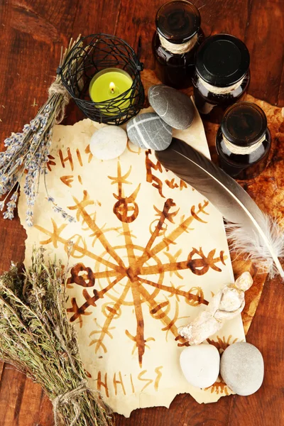 Composition with old papers, herbs, stones and bottles with symbols on wooden background — Stock Photo, Image