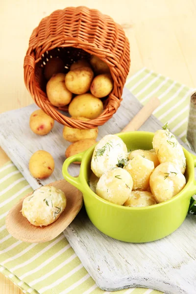 Bud unge kartofler med creme fraiche og urter i gryde på træplade på bordet close-up - Stock-foto