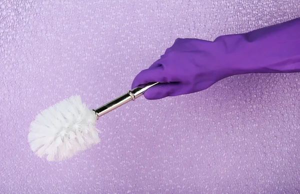 Toilet brush in hand on purple background — Stock Photo, Image